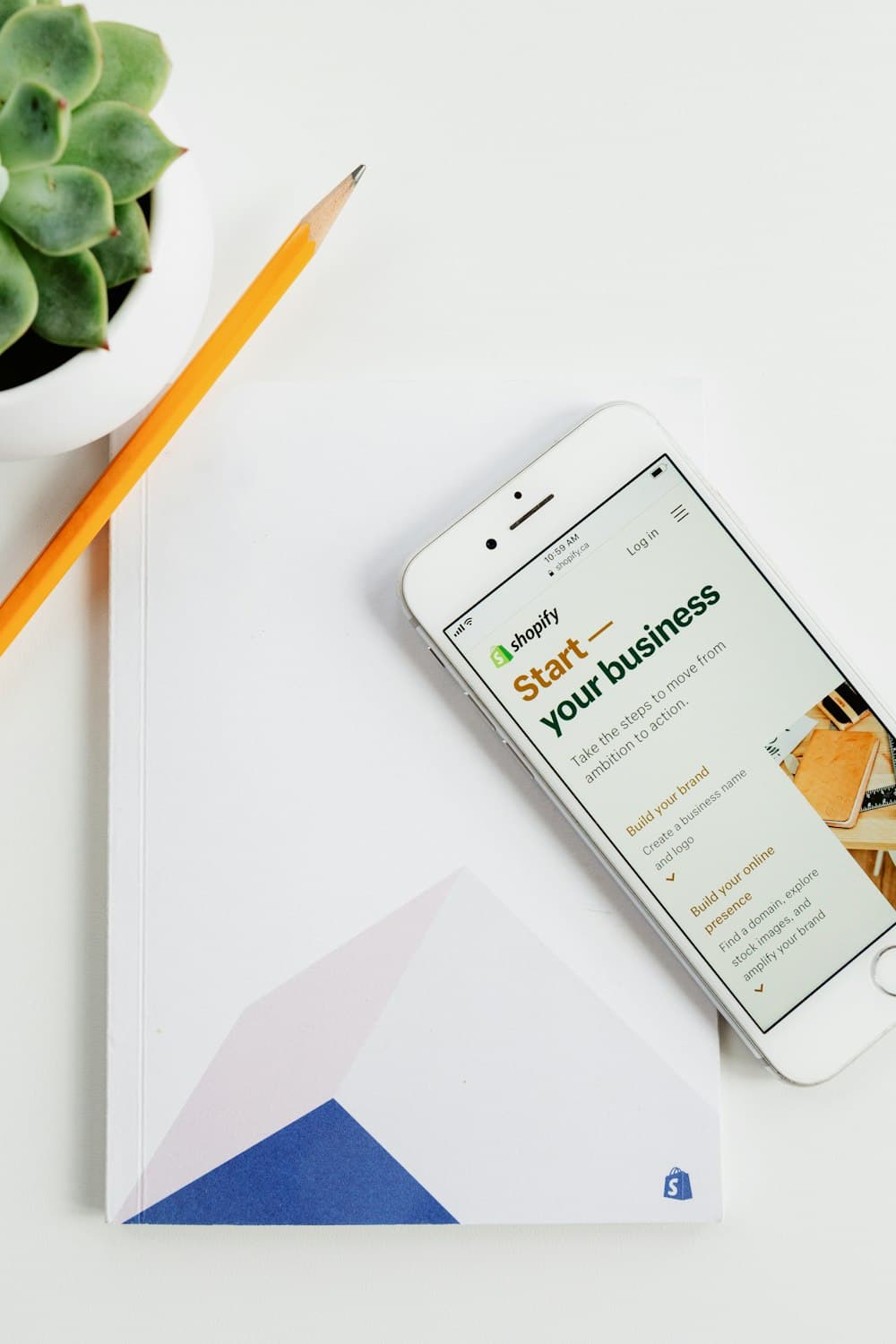 A phone showing 'Start your business' next to a notebook and pencil